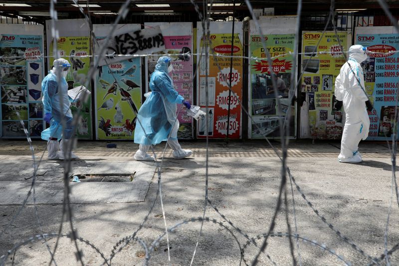 &copy; Reuters. FILE PHOTO: Medical workers wearing protective suits pass by barbed wire at the red zone under enhanced lockdown, amid the coronavirus disease (COVID-19) outbreak, in Petaling Jaya