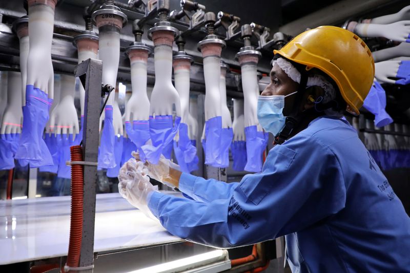 © Reuters. FILE PHOTO: A worker inspects newly-made gloves at Top Glove factory in Shah Alam