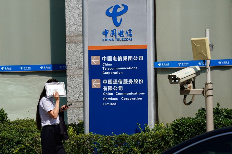 &copy; Reuters. FILE PHOTO: FILE PHOTO: Woman shields herself from the sun as she walks past an office building of China Telecom, in Beijing