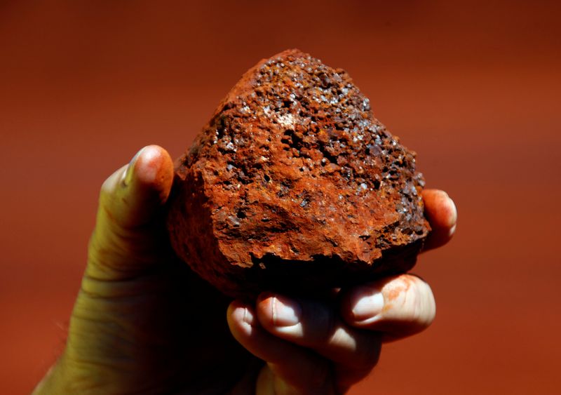 © Reuters. FILE PHOTO: A miner holds a lump of iron ore at a mine located in the Pilbara region of Western Australia