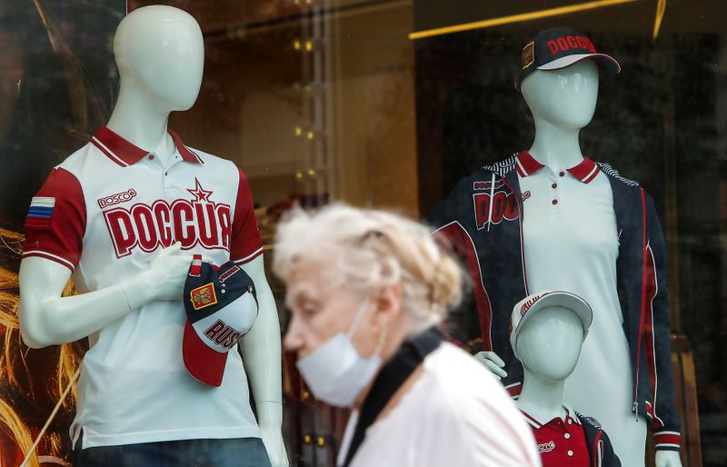 &copy; Reuters. An elderly woman wearing a protective face mask walks past mannequins in a show-case in Moscow