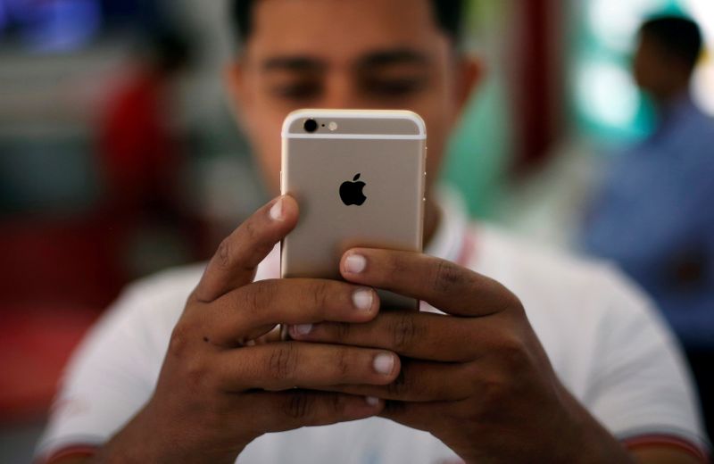 © Reuters. FILE PHOTO: A salesman checks a customer's iPhone at a mobile phone store in New Delhi