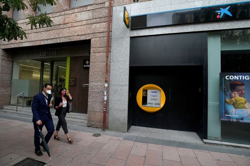 © Reuters. People walk past branches of Bankia and Caixabank in Madrid