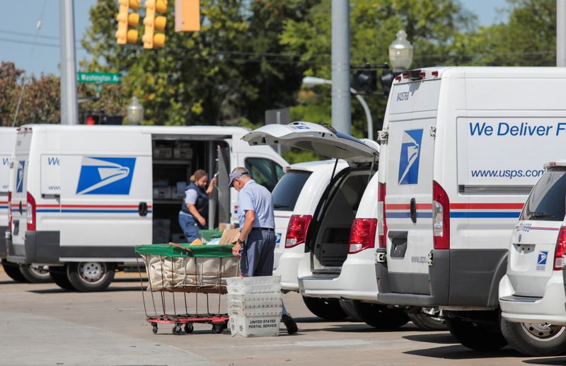 © Reuters. United States Postal Service (USPS) workers load mail into delivery trucks outside a post office in Royal Oak