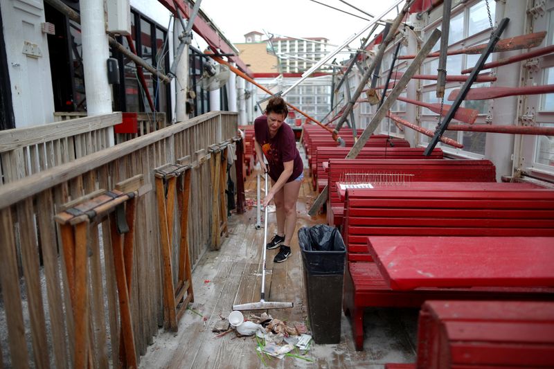 &copy; Reuters. FILE PHOTO: Vanessa Levan, a server at Crabs sweeps debris after Hurricane Sally in Pensacola Beach, Florida