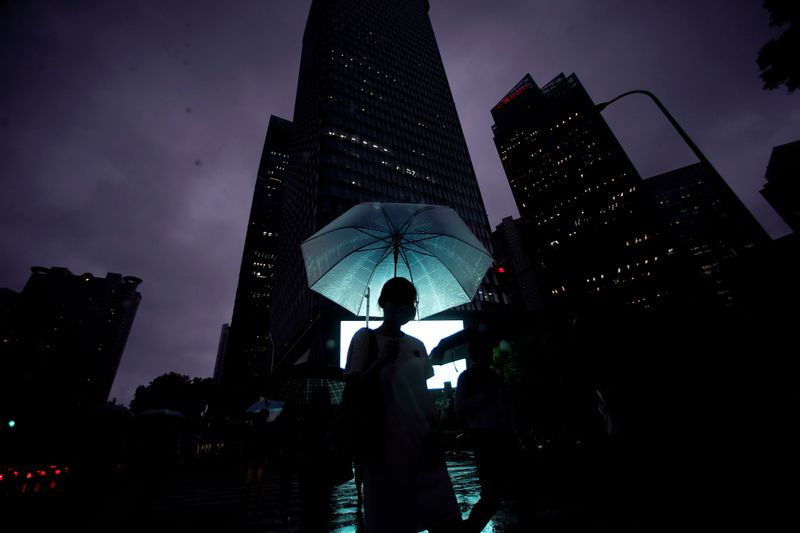 &copy; Reuters. A woman walks with an umbrella in Lujiazui financial district in Pudong
