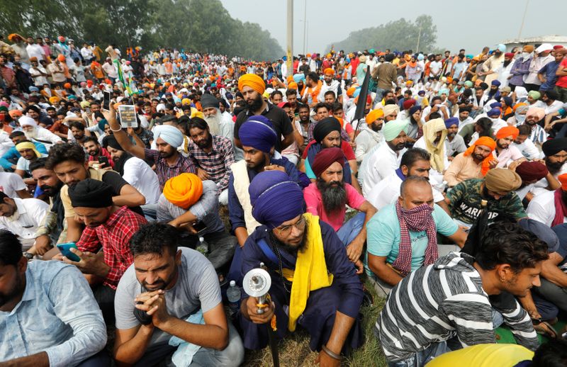 © Reuters. FILE PHOTO: Farmers sit on a road as they block a national highway during a protest against farm bills passed by India's parliament, in Shambhu