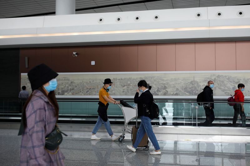 &copy; Reuters. Passengers wearing face masks following the coronavirus disease (COVID-19) outbreak walk at the Beijing Daxing International Airport ahead of Chinese National Day holiday, in Beijing