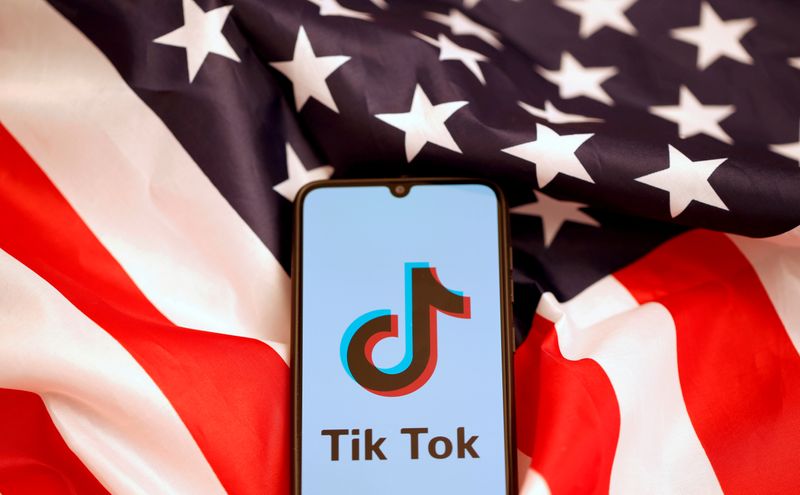 &copy; Reuters. Ilustración fotográfica con el logo de TikTok en un móvil frente a una bandera estadounidense.