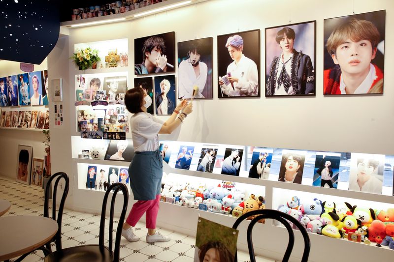 &copy; Reuters. Cafe owner Kim Eun-hee, fan of K-pop boy band BTS, wipes the dust off the picture frame in her cafe in Seoul