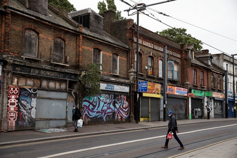&copy; Reuters. Pedestrians walk past shuttered and bordered up retails stores in Croydon, south London