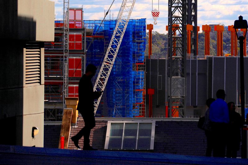 &copy; Reuters. Pedestrians walk in front of a crane and scaffolding on a construction site in central Sydney