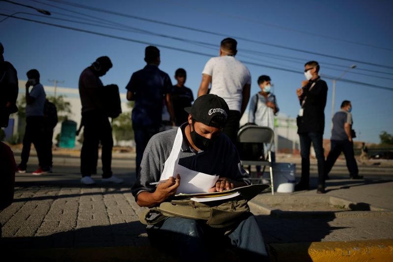 © Reuters. FILE PHOTO:  A job seeker checks a job application form for an assembly factory as the coronavirus disease (COVID-19) outbreak continues in Ciudad Juarez