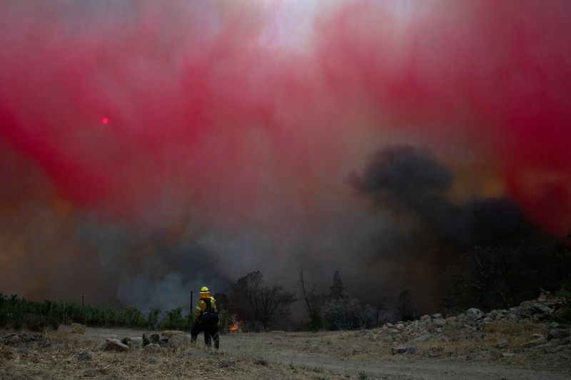 &copy; Reuters. Firefighter stands under cloud of red retardant dropped on the Glass Fire in Deer Park, California