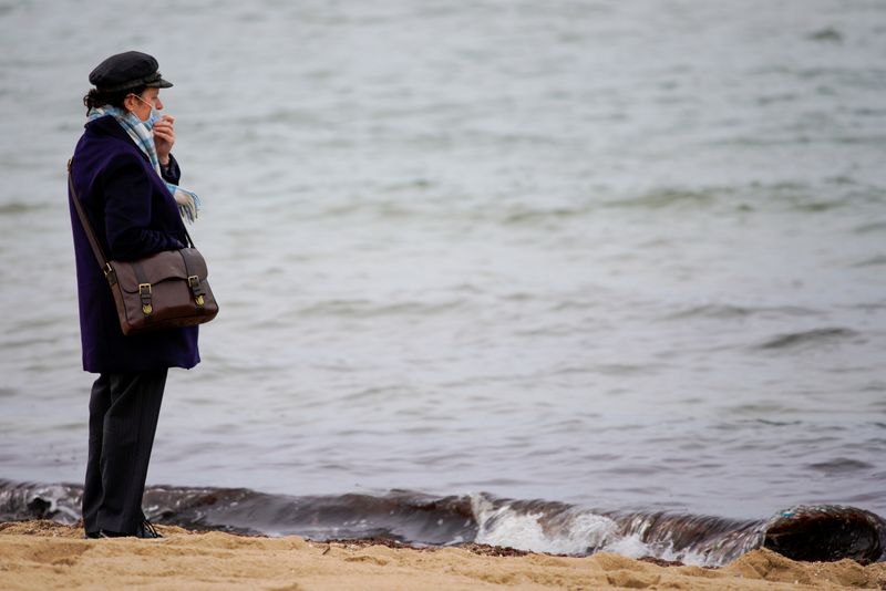 &copy; Reuters. FILE PHOTO: A woman wears a face mask at St Kilda beach in Melbourne, the first city in Australia to enforce mask-wearing to curb a resurgence of COVID-19