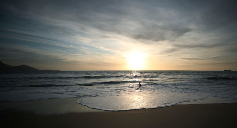 © Reuters. FILE PHOTO: A lone bather takes in the winter sun at a beach in Cape Town, South Africa, during the coronavirus disease (COVID-19) outbreak