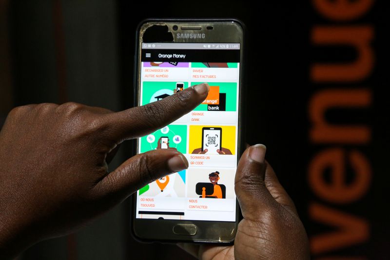 © Reuters. A woman prepares to perform a financial transaction on her mobile phone at a bank of the French mobile operator Orange in Abidjan, Ivory Coast