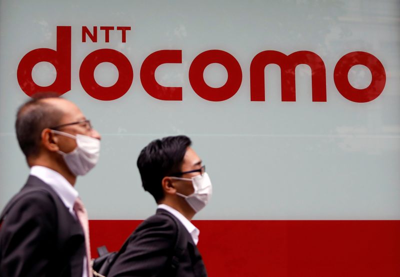 © Reuters. Passersby wearing protective face masks walk past in front of NTT Docomo shop in Tokyo, Japan