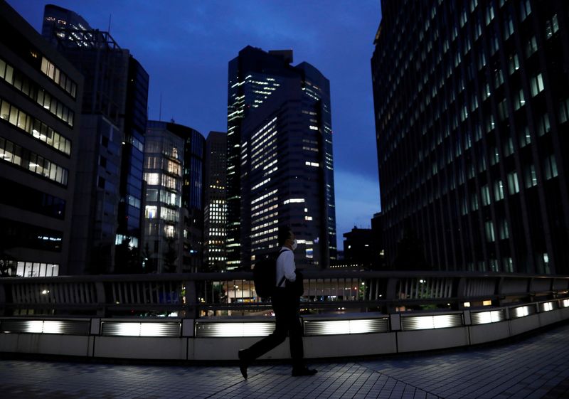 &copy; Reuters. FILE PHOTO: A worker wearing a protective face mask walks past office buildings in the background, during the global outbreak of the coronavirus disease (COVID-19), in Tokyo