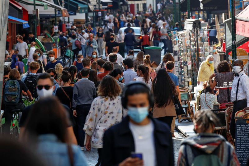 © Reuters. FILE PHOTO: People wearing protective face masks walk in a busy street in Paris