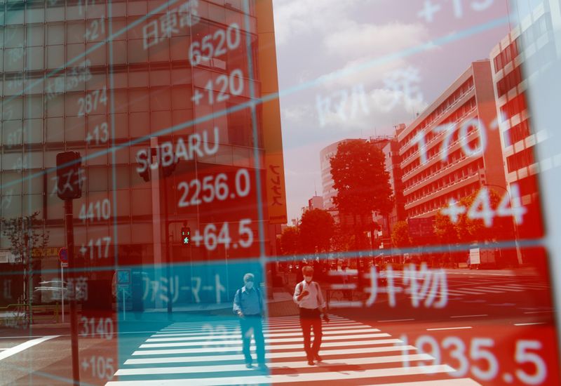 &copy; Reuters. Due passanti riflessi su uno schermo con dati sulla Borsa di Tokyo