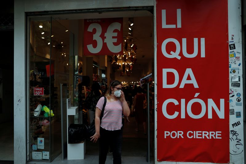 &copy; Reuters. A woman adjusts her face mask as she walks out of a store advertising going-out-of-business sales, amid the coronavirus disease (COVID-19) outbreak, in Madrid