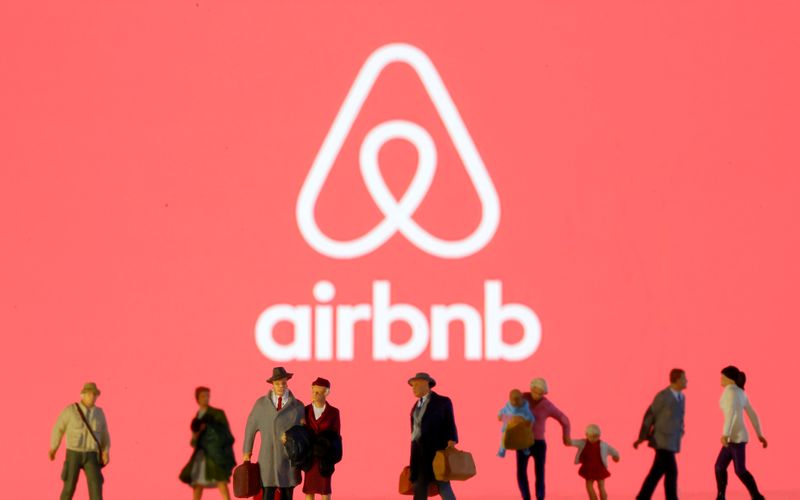 &copy; Reuters. Small toy figures are seen in front of diplayed Airbnb logo