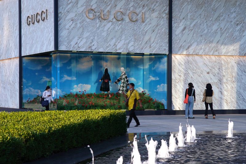 © Reuters. People wearing face masks following the COVID-19 outbreak walk past a store of Italian luxury brand Gucci at a shopping complex in Beijing