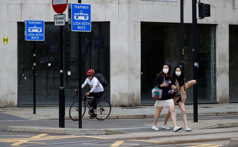 &copy; Reuters. People wearing protective face coverings walk past an empty retail unit following the outbreak of the coronavirus disease (COVID-19), in Manchester, Britain