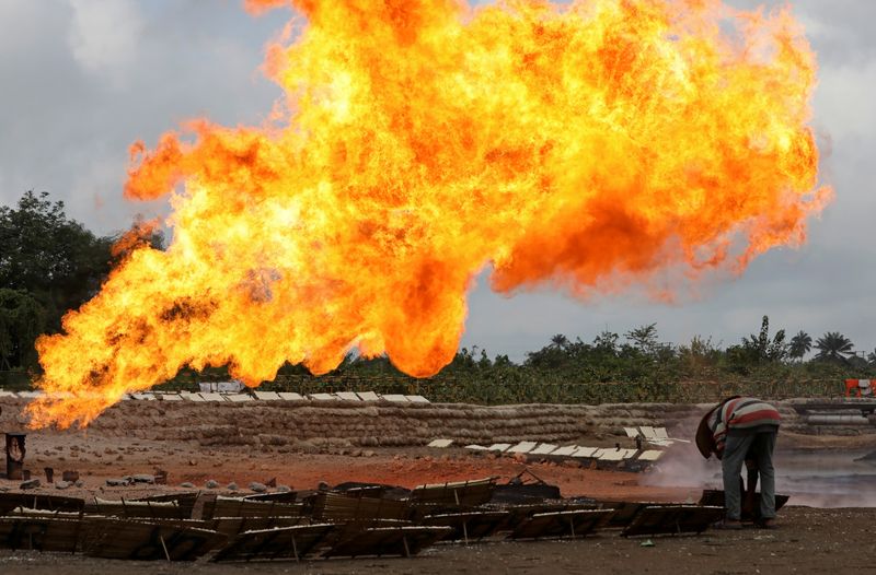 &copy; Reuters. A man sets a wooden tray of tapioca on the ground close to a gas flaring furnace at a flow station in Ughelli, Delta State