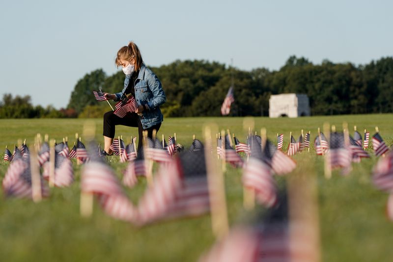 © Reuters. FILE PHOTO: American flags representing 200,000 lives lost due to coronavirus are placed on National Mall in Washington