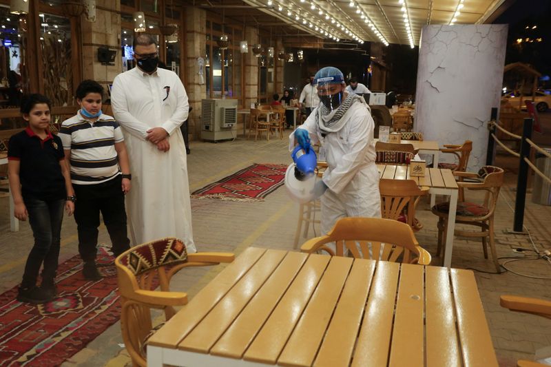 &copy; Reuters. A worker wears a protective suit, following the outbreak of the coronavirus disease (COVID-19), sterilizes the tables before the customers sit down after a restaurant reopened, in Riyadh