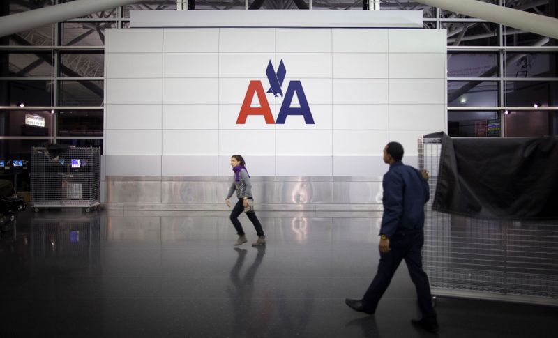 &copy; Reuters. FILE PHOTO: People walk past an American Airlines logo at John F. Kennedy (JFK) airport in in New York