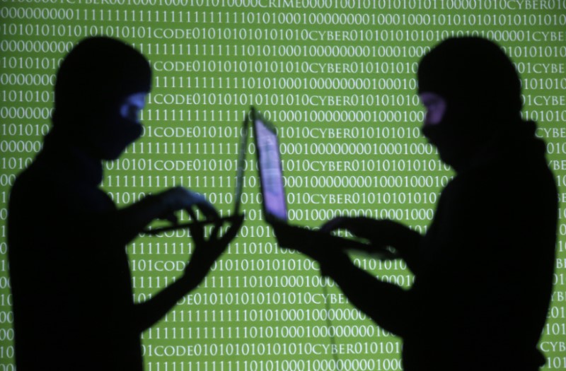 &copy; Reuters. Picture illustration of People posing with laptops in front of projection with word &apos;cyber&apos; and binary code in Zenica
