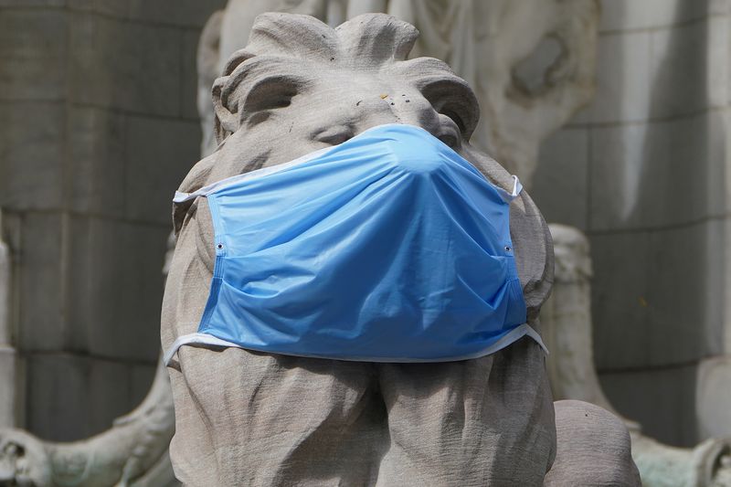 &copy; Reuters. A lion statue that sits outside the New York Public Library building wears a mask