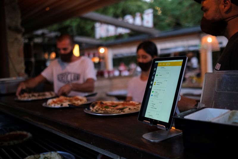 &copy; Reuters. FILE PHOTO: Employees pick up the pizzas near an IPad with the &quot;Funky Pay&quot; app, at Funky Pizza restaurant, where the app replaces waiters, in Palafrugell