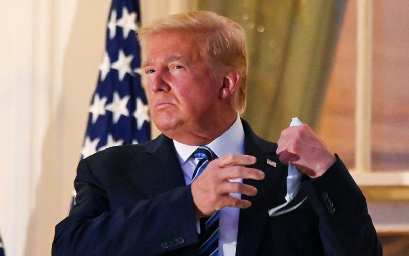 © Reuters. U.S. President Donald Trump pulls off his face mask as he returns to the White House after being hospitalized at Walter Reed Medical Center for coronavirus disease (COVID-19), in Washington