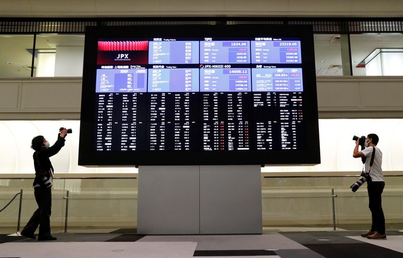 &copy; Reuters. Dei fotografi scattano accanto a uno schermo che mostra l&apos;andamento dei titoli all&apos;interno della Borsa di Tokyo