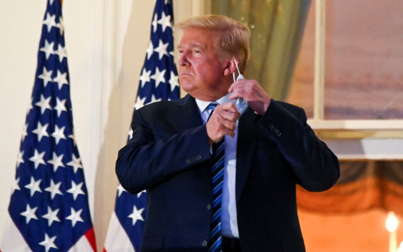 © Reuters. U.S. President Donald Trump pulls off his face mask as he returns to the White House after being hospitalized at Walter Reed Medical Center for coronavirus disease (COVID-19), in Washington