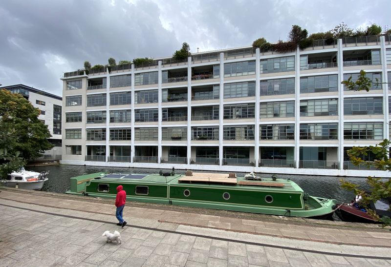 &copy; Reuters. A person walks their dog past a canal boat and a block of flats in London