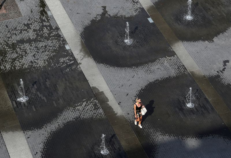 © Reuters. A woman walks among fountains on a square in central city during a hot summer day in Brussels
