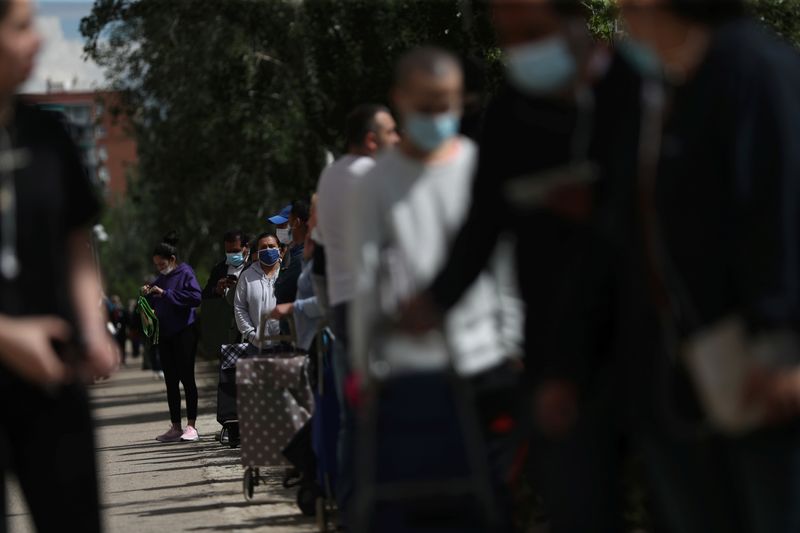 © Reuters. FILE PHOTO: People queue to receive donated food from volunteers of Vecinos Parque Aluche association as the spread of the coronavirus disease (COVID-19) continues in Madrid