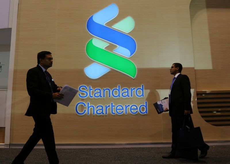 &copy; Reuters. People pass by the logo of Standard Chartered plc at the SIBOS banking and financial conference in Toronto