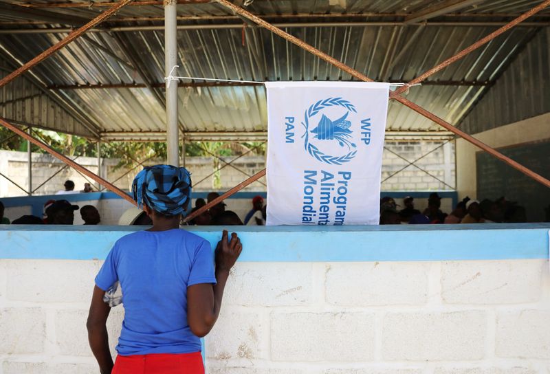 © Reuters. FILE PHOTO: A woman watches as money is distributed by the World Food Programme in Bainet