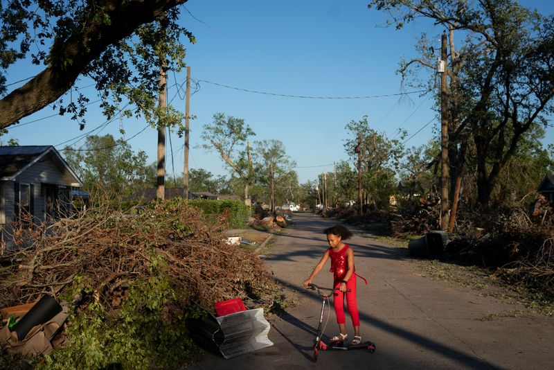© Reuters. Iyana Sells, 9, plays on her street which is still lined with debris from Hurricane Laura the day after Hurricane Delta swept through Lake Charles