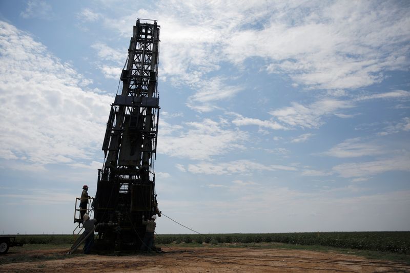 &copy; Reuters. Oil field workers prepare a swabbing rig in a cotton field in Seminole