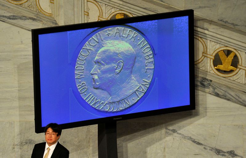 © Reuters. A guest stands next to a screen showing the Nobel Prize medal during the Nobel Peace Prize ceremony in Oslo