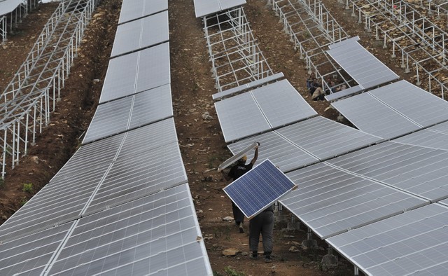 &copy; Reuters. FILE PHOTO:  Workers carry solar panels as they work at a solar power plant which is under construction on a hill in Wuhu