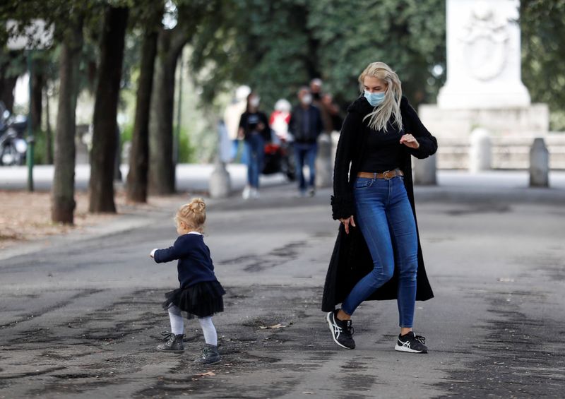 &copy; Reuters. Mulher usando máscara brinca com criança em Roma