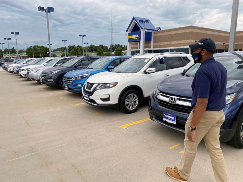 © Reuters. FILE PHOTO: Brandon Parrum, general manager of CarMax's Des Moines store, walks past vehicles that customers can arrange to buy online and collect at the store using 